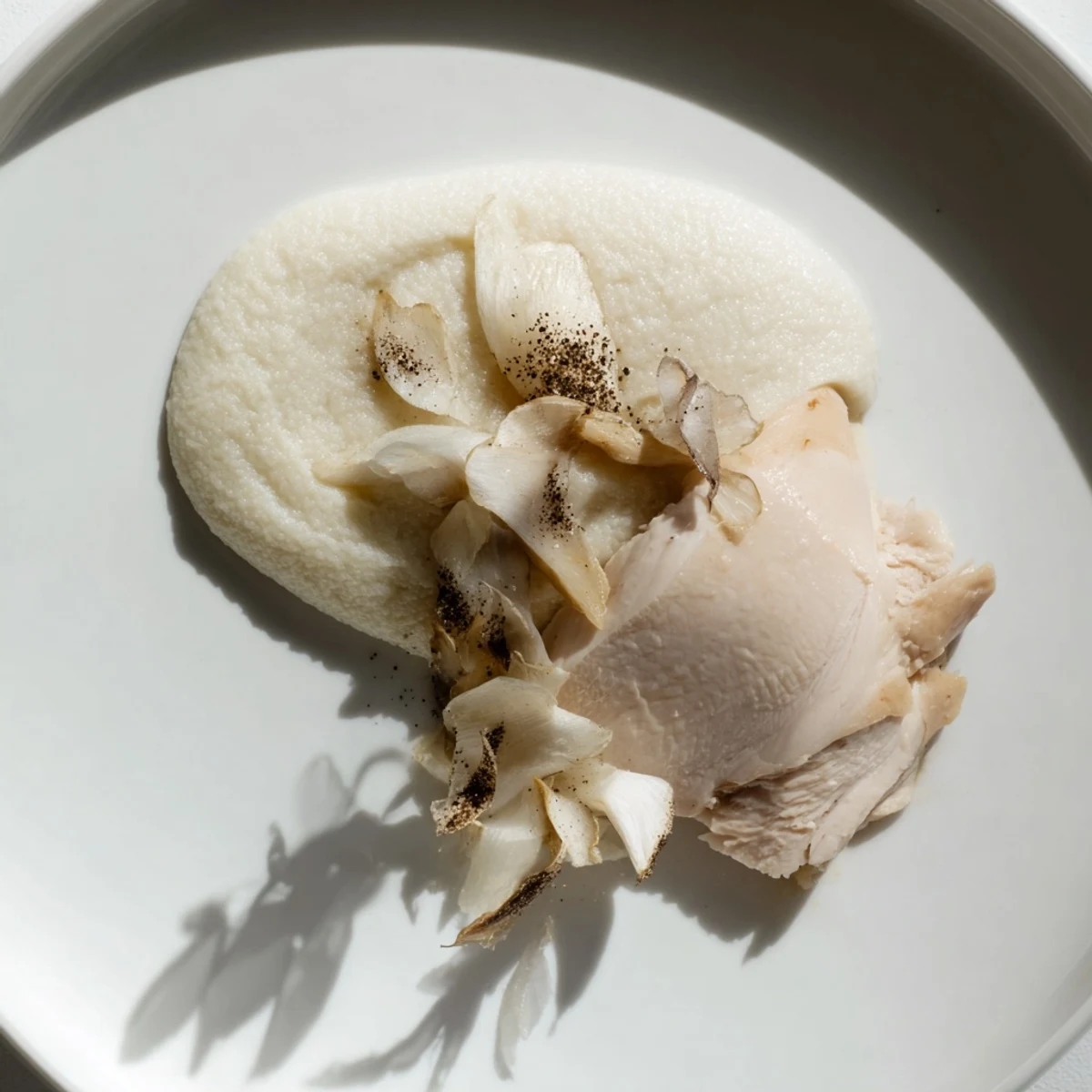 Pale sautéed mushrooms accent the beautifully plated The Ghostly Gala, a sophisticated white dinner with pepper shadows.