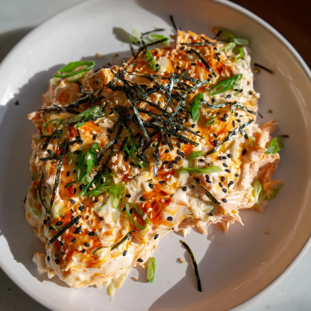 Deconstructed Creamy Salmon Sushi Bake topped with creamy sauce, sesame seeds, and fresh scallions served warm.