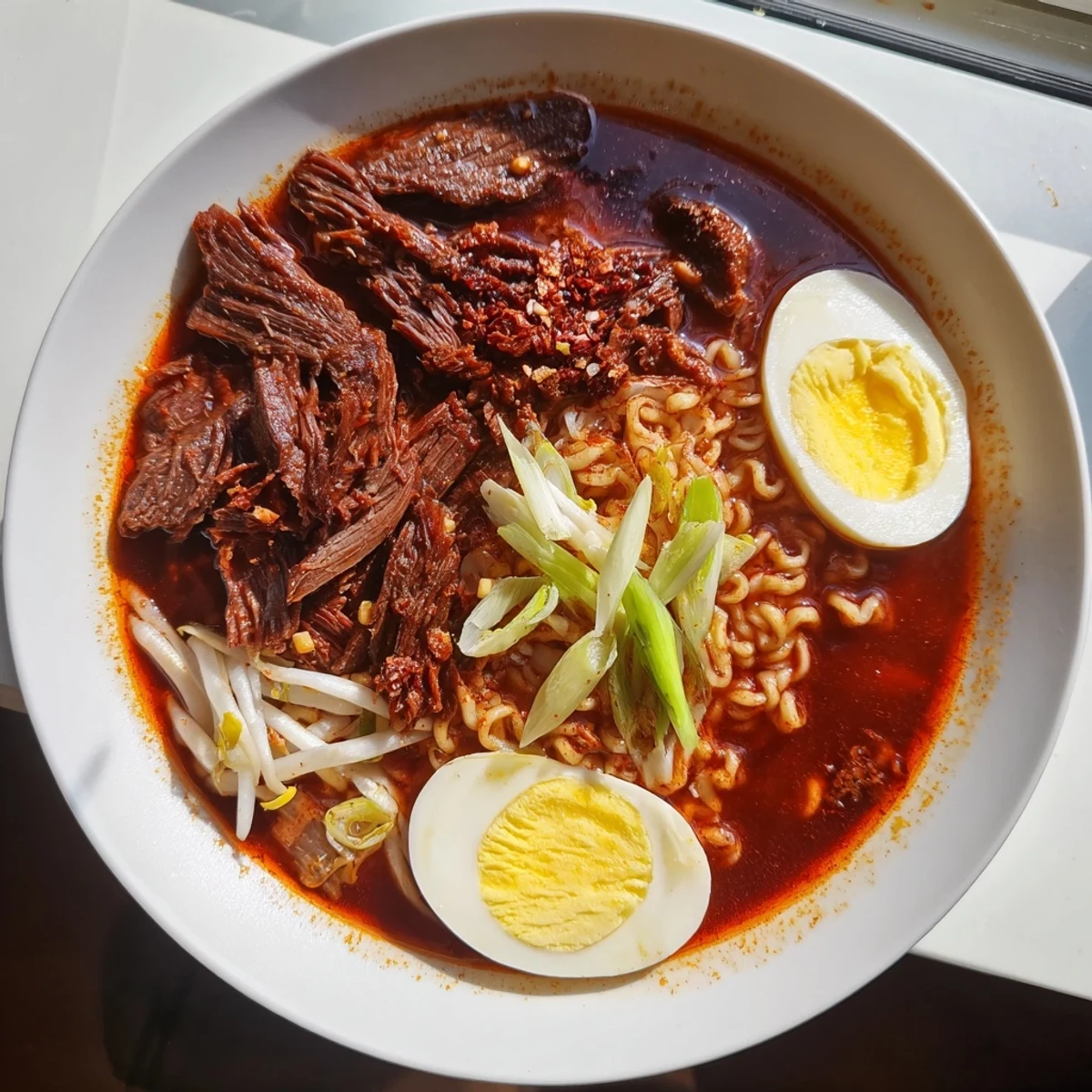Delectable birria ramen, with savory shredded beef and a flavorful broth served in steaming ramen bowls.