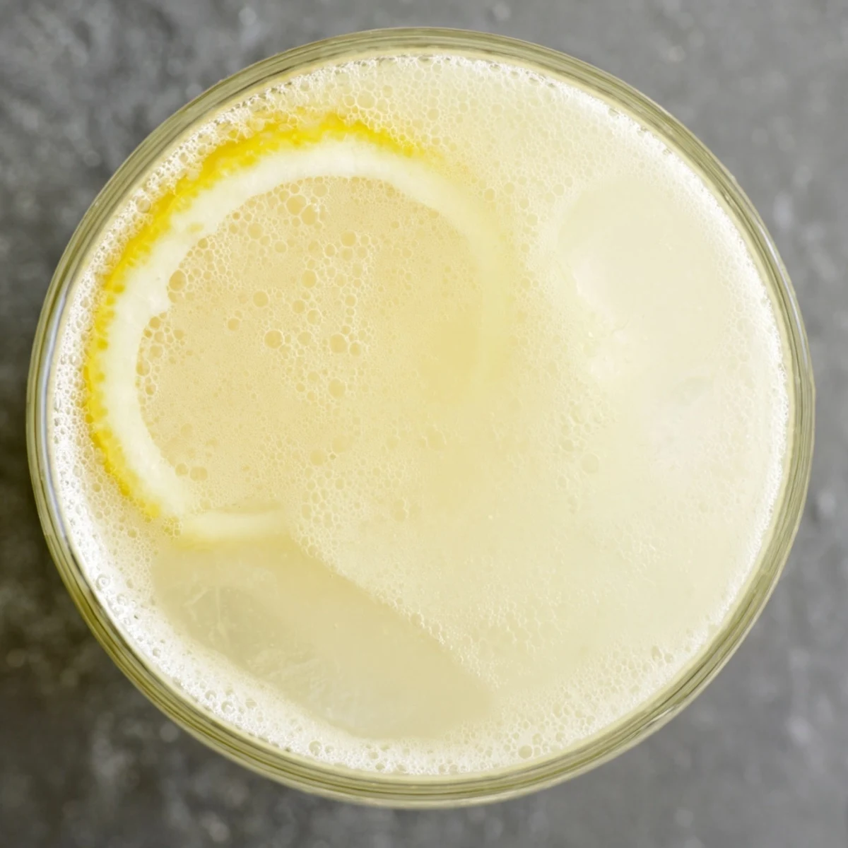 The creamy lemonade drink is layered over ice in a clear glass, garnished with fresh mint and lemon slices.