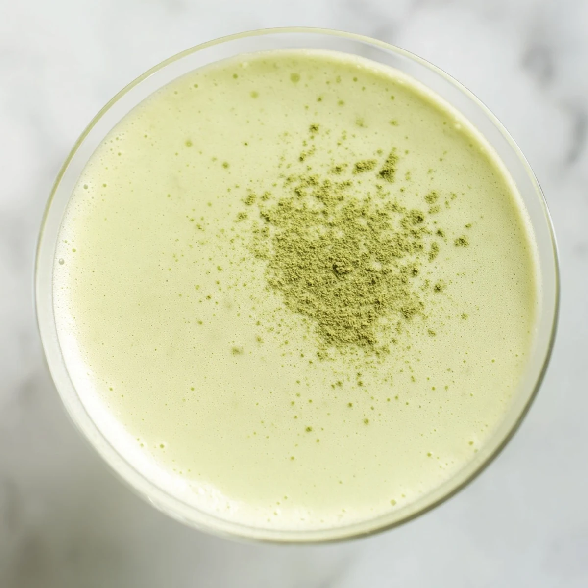 A frothy Matcha Martini Cocktail in a chilled glass, topped with a light dusting of green matcha powder for garnish.