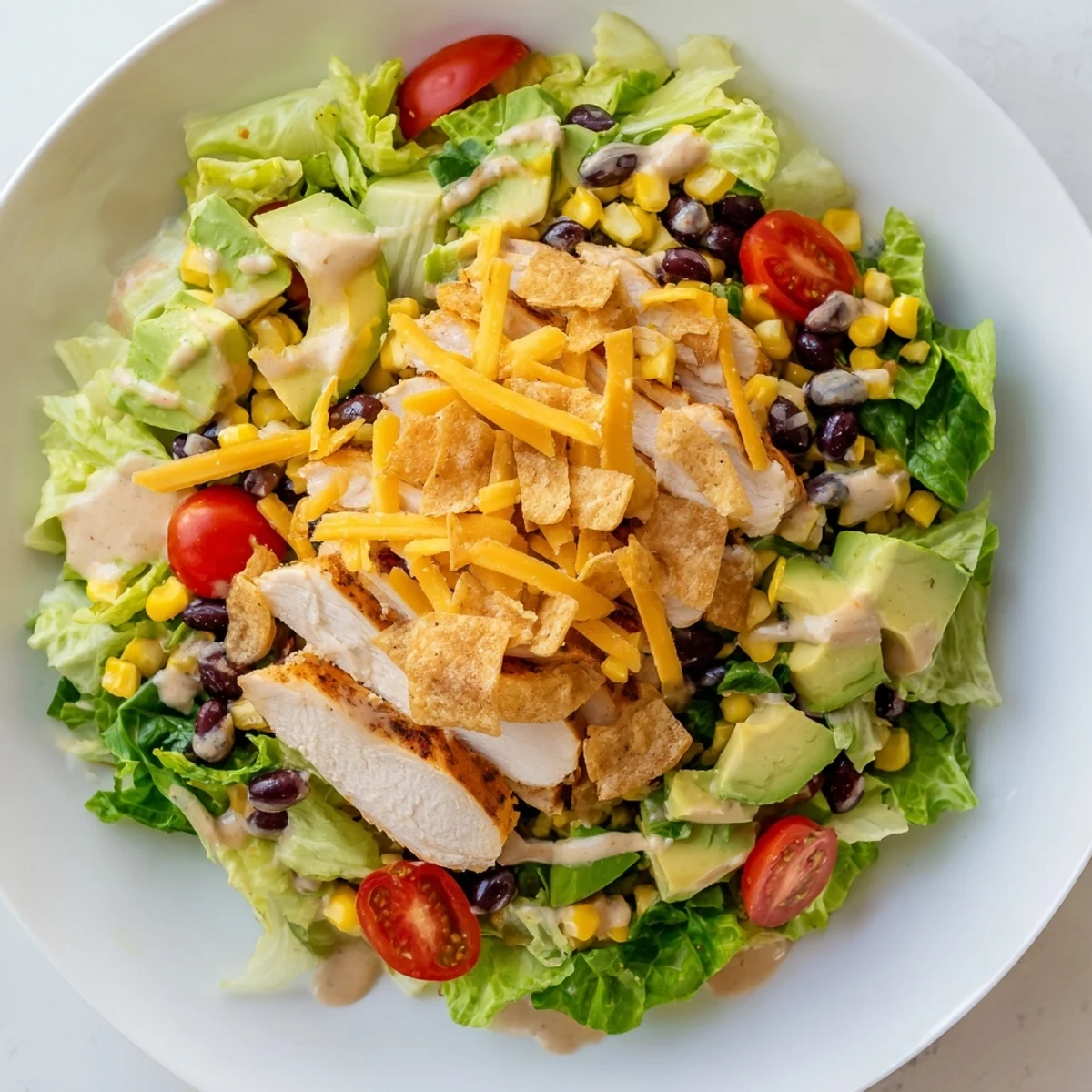 A vibrant Crunchy Taco Chicken Salad with seasoned chicken, crisp lettuce, corn, and avocado topped with crushed shells.