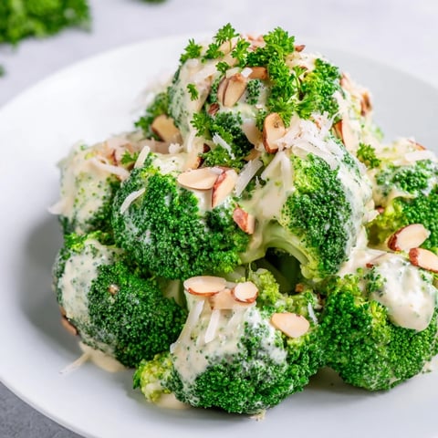 Bright green blanched broccoli florets glistening with creamy garlic-Parmesan dressing, topped with toasted almonds and fresh parsley.  