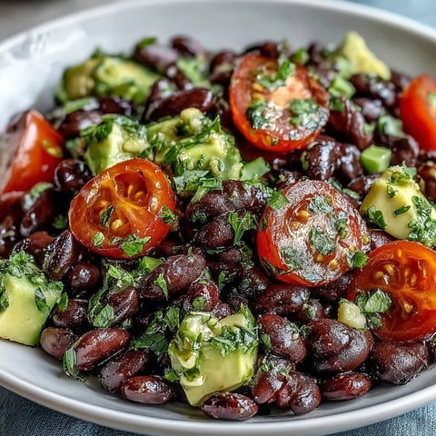 A vibrant Black Bean and Veggie Bowl topped with creamy diced avocado, fresh cilantro, and a zesty lime dressing.