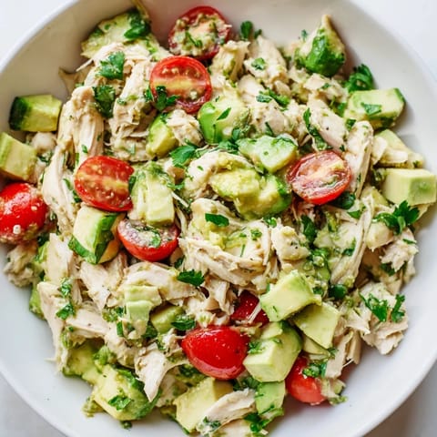 Vibrant avocado chicken salad featuring crunchy cucumbers, zesty lime dressing, and soft shredded chicken for a light, refreshing meal.  
