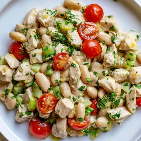A colorful bowl of Lemony White Bean Chicken Salad featuring tender chicken, white beans, cherry tomatoes, and fresh dill, ready for a light lunch or picnic.
