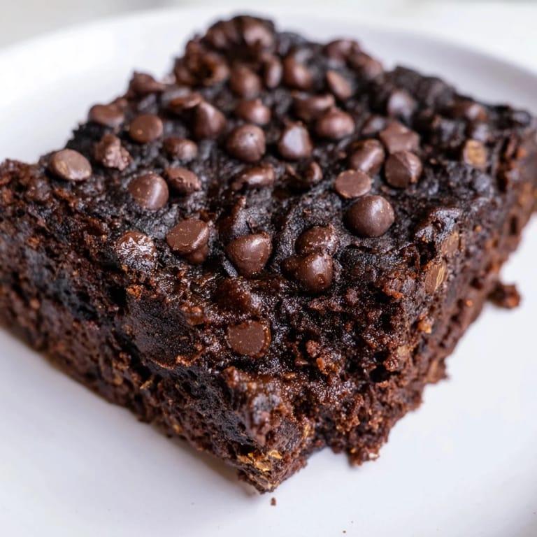 Square of baked Greek Yogurt Brownies with melted chocolate chips, ready for a delicious treat.
