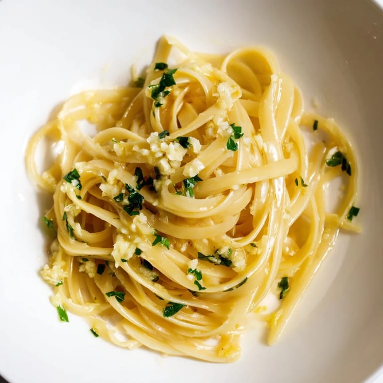 Savory Garlic Butter Linguine with fresh parsley, plated and ready to serve with lemon wedges.