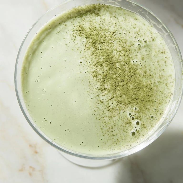 Close-up of a creamy Matcha Martini Cocktail, the matcha swirling through vodka and cream inside a clear martini glass.