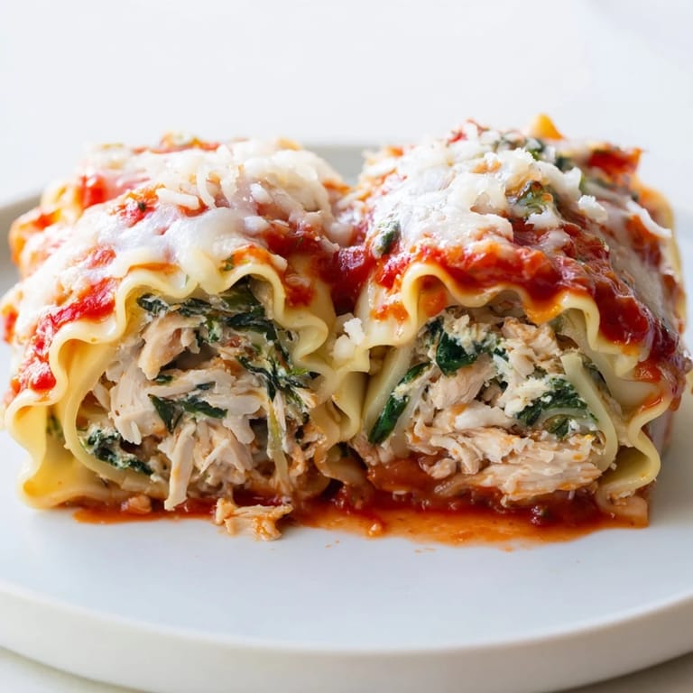 Close-up of a sliced Chicken and Spinach Lasagna Roll revealing layers of tender pasta, cheesy chicken, and vibrant green spinach filling.