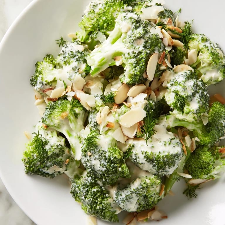 Tossed garlic-Parmesan broccoli salad with crunchy almonds and grated cheese, perfect for summer picnics or a light vegetarian lunch.