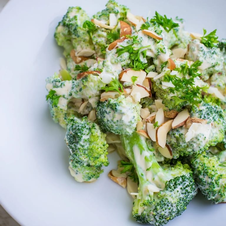 Vibrant broccoli salad with cherry tomatoes, red onion, and a rich garlic-Parmesan sauce, served chilled for a refreshing side.  